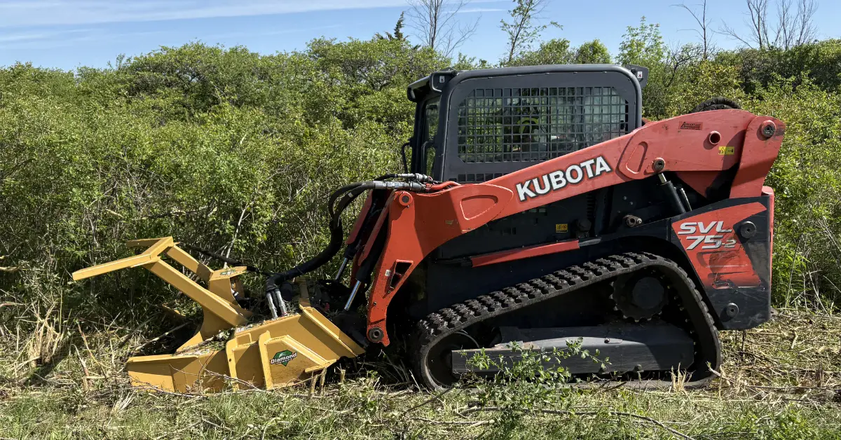 A Kubota compact track loader with a mulching head clearing dense shrubby growth from a property in Southwestern Ontario.